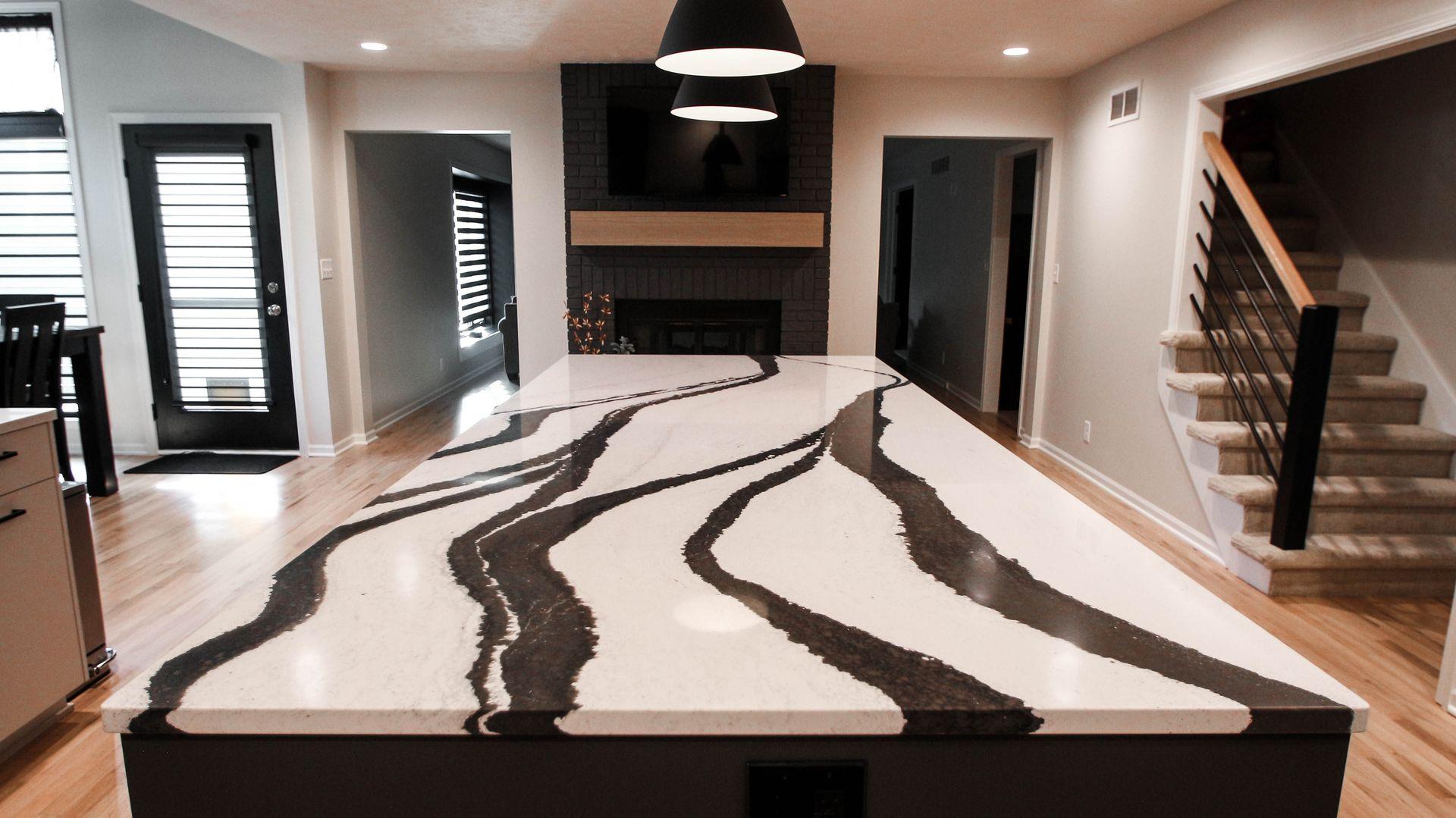 Modern kitchen with large marble island, black and white striped design, and wood flooring.