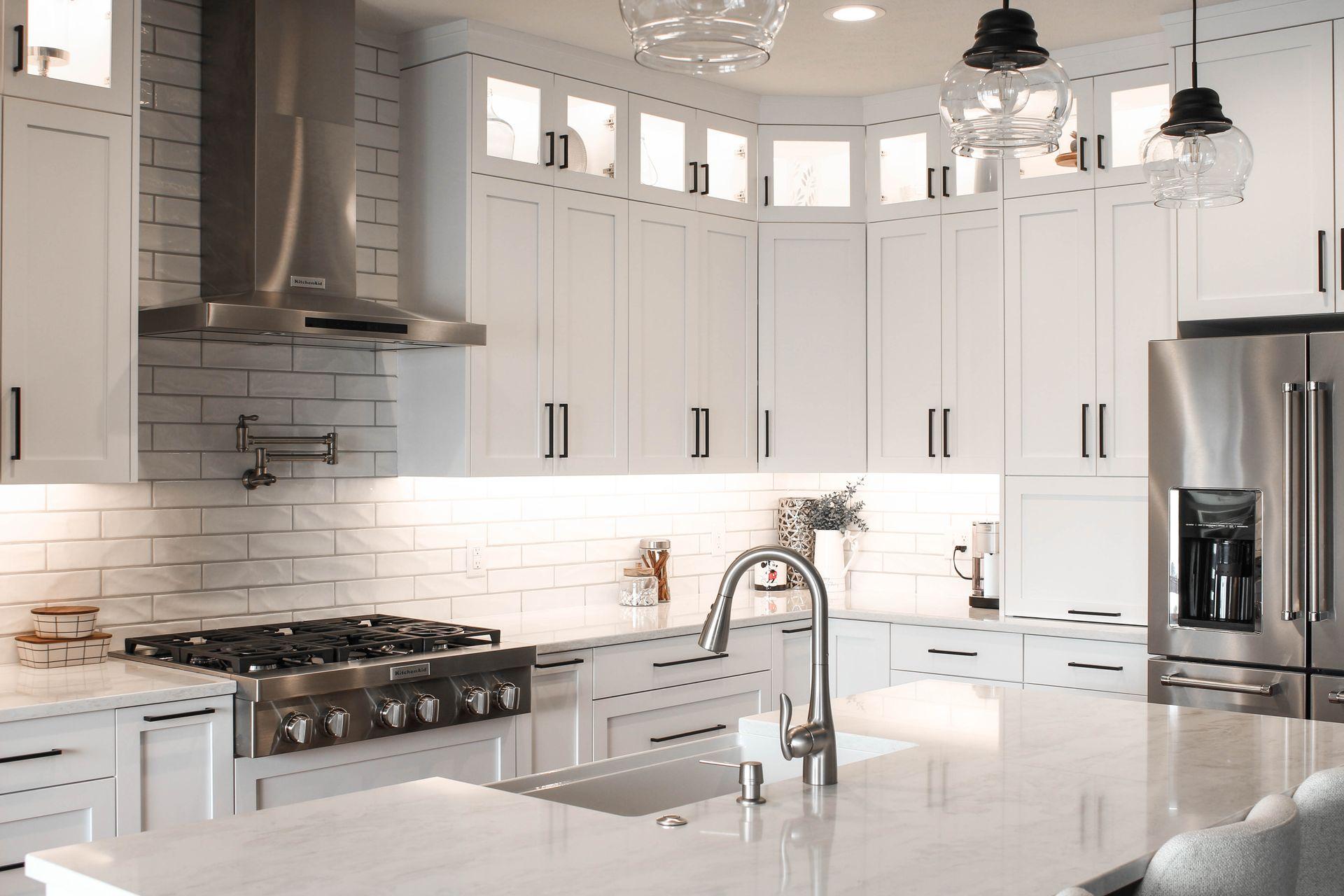 Modern kitchen with white cabinets, stainless steel appliances, and a marble countertop island.