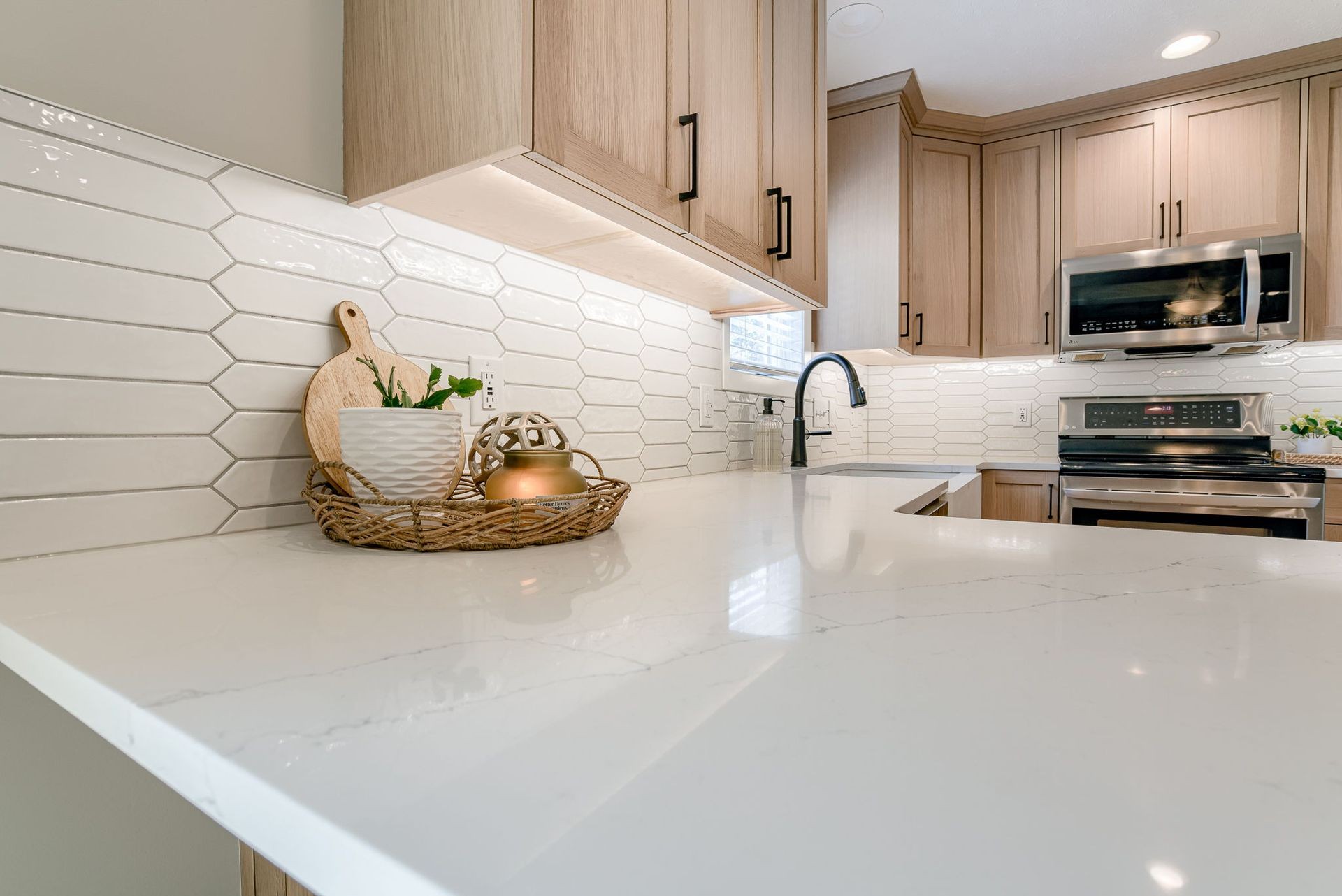 Modern kitchen with white countertops, wooden cabinets, and hexagon tile backsplash.